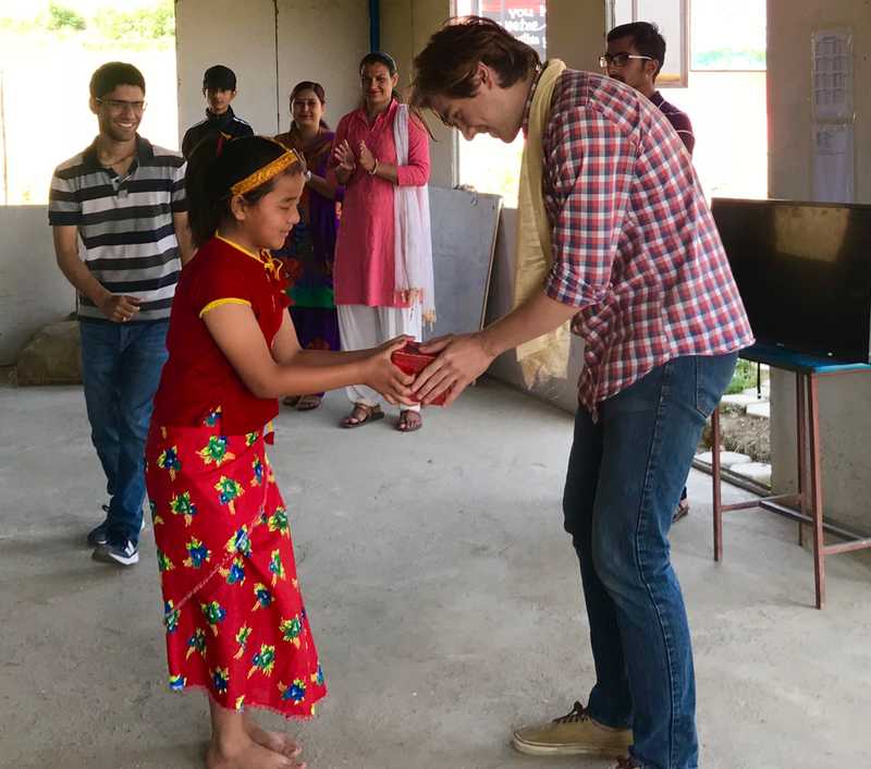 A student in cultural dress giving gift to her teacher